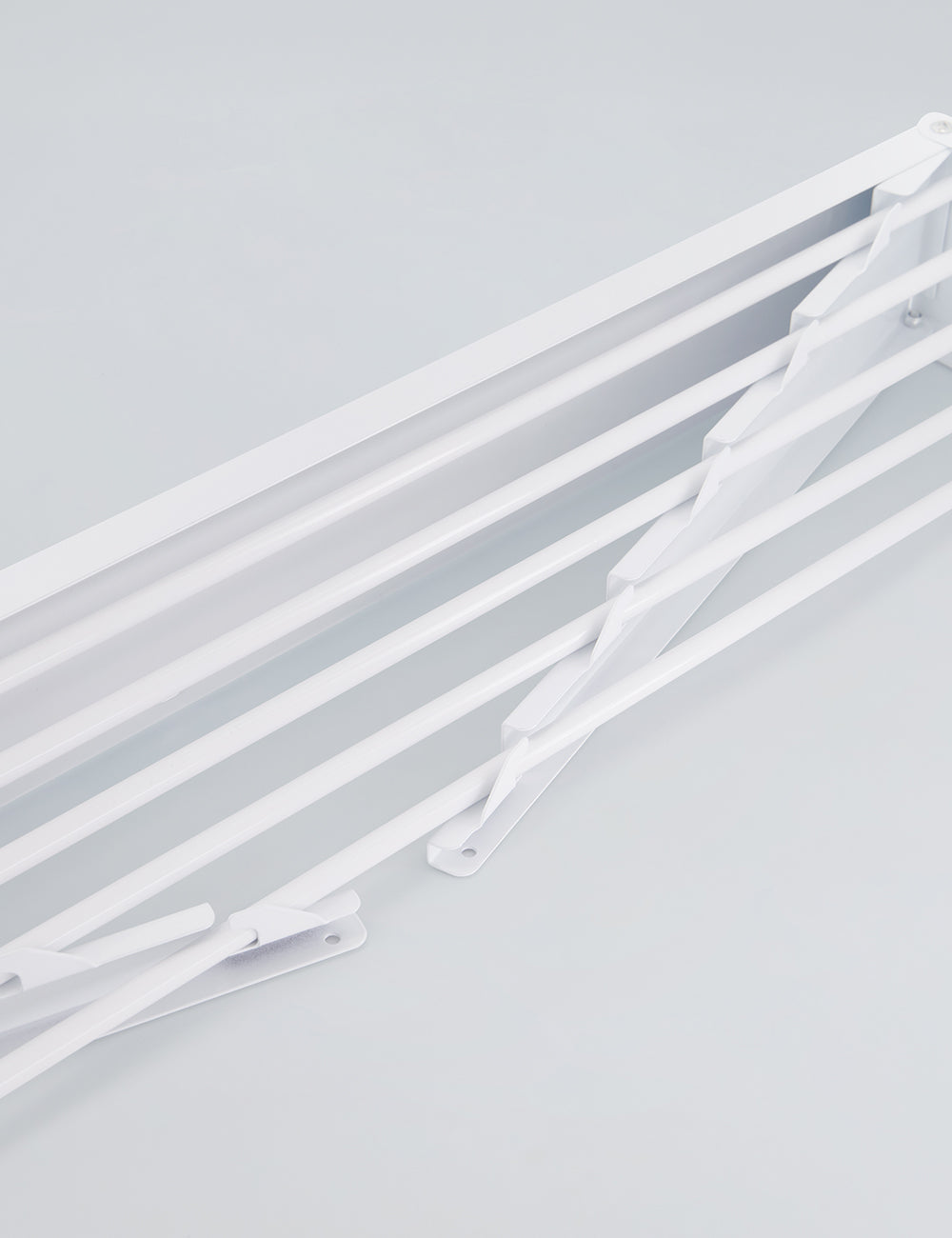 White wall mounted drying rack with laundry hanging to dry